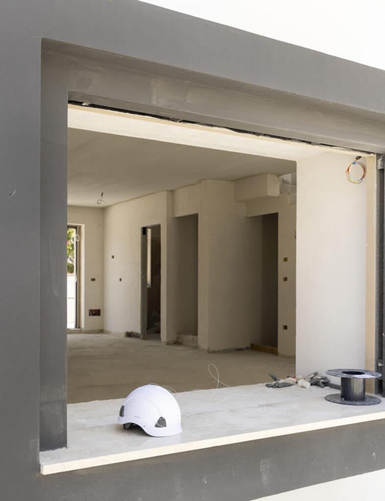 White hard Safety helmet on the window sill in a new house construction site. Protection equipment