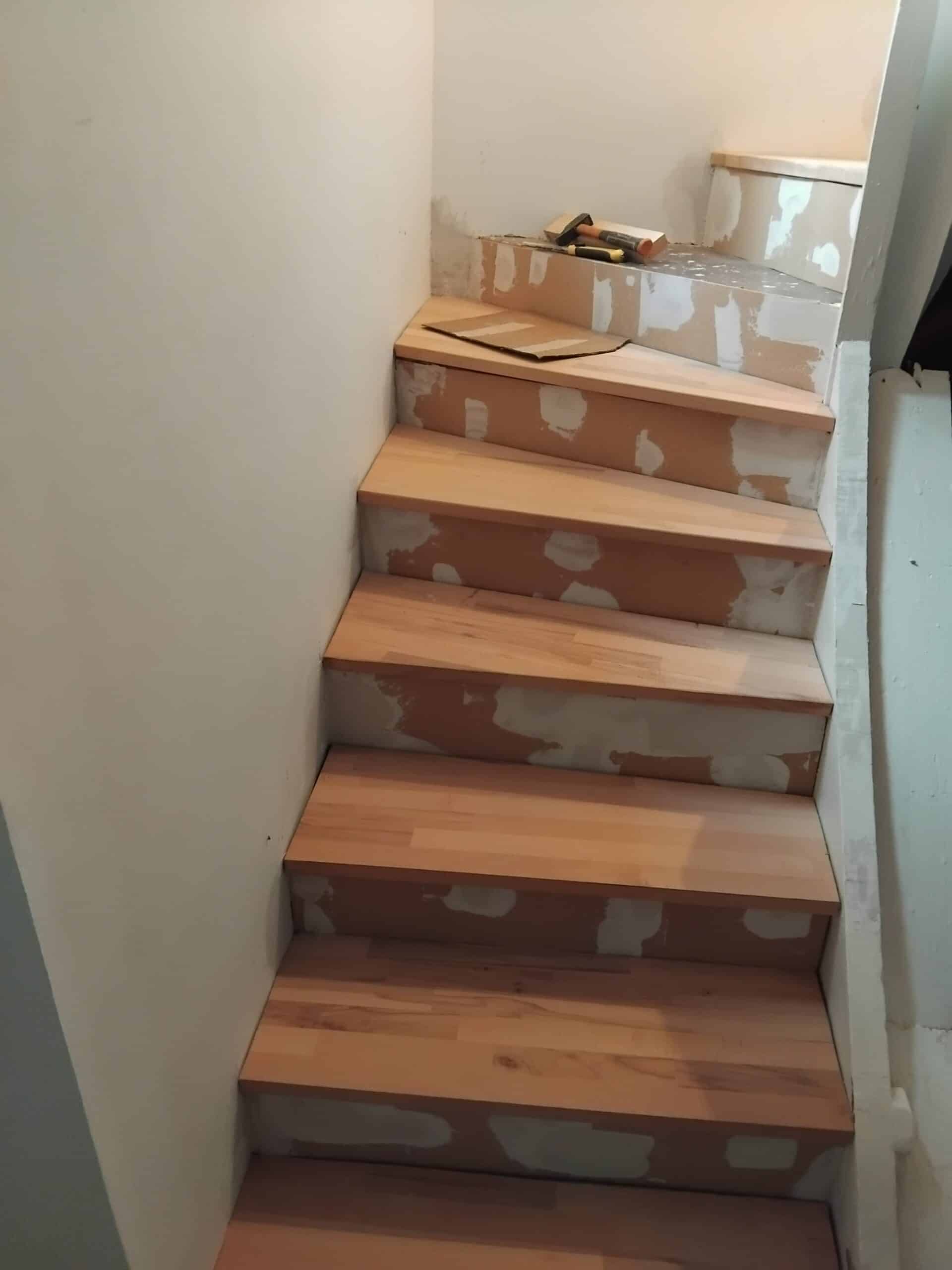 Rénovation d'un escalier tournant avec marches en bois clair et contremarches enduites de plâtre blanc.